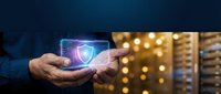 Cybersecurity expert holding glowing shield hologram in data center environment, representing digital protection and network security technology solutions.