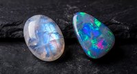Two stunning opal gemstones displaying vibrant blue and green fire patterns on dark textured surface for jewelry design and luxury collection concepts.