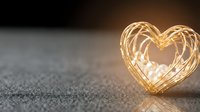 Glowing golden heart-shaped light trail on textured surface creates romantic atmosphere for Valentine's Day celebrations and love-themed designs.