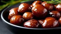 Glossy marinated olives in dark bowl with fresh herbs, Mediterranean appetizer ready for gourmet cooking and culinary presentations.