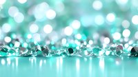 Sparkling turquoise crystals and beads scattered on reflective surface with soft bokeh lights creating magical atmosphere. Luxury party decoration background.