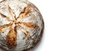 Freshly baked artisan sourdough bread with rustic crust and star-shaped scoring pattern on white background, perfect for food marketing.