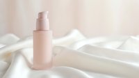 Cosmetic spray bottle in soft pink on white fabric background, suitable for skincare, beauty product packaging, and cosmetics marketing.