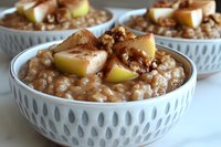 Creamy rice pudding topped with caramelized apples and crushed walnuts served in ceramic bowl with geometric pattern, comfort food dessert photography.