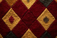Knitted wool pattern in burgundy red and golden yellow diamond shapes creates cozy winter texture with geometric argyle design and rich color contrast.