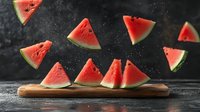 Fresh juicy watermelon slices floating in dark space above wooden cutting board with water drops and dramatic lighting, summer refreshment concept.