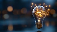 Glowing light bulb with magical sparkles and energy flowing inside against dark bokeh background, symbolizing innovation and creative inspiration.