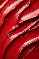 Glossy red lipstick smear texture with shimmering particles, close-up macro shot for cosmetic advertising and beauty content.