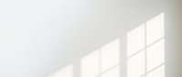 Sunlight streaming through window panes casting geometric shadows on white wall, creating minimalist interior lighting effect for design and architectural projects.
