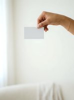Close-up of a hand holding a blank white card against a neutral background, suitable for branding, business cards, invitations, and marketing materials.