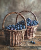 Fresh ripe blueberries in traditional woven wicker baskets on rustic wooden table against textured wall background, moody natural lighting.