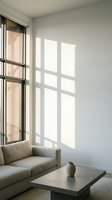 Minimalist living room with beige upholstered sofa, concrete coffee table, and natural light streaming through floor-to-ceiling windows with vertical blinds casting geometric shadows on white walls.