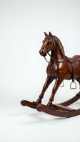 Vintage wooden rocking horse with leather saddle and brass stirrups, isolated on white background, classic handcrafted toy for nursery decor.