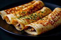 Savory crepes filled with mushrooms and herbs, garnished with fresh parsley on dark plate, close up view showing golden brown crispy texture.