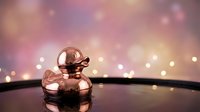 Elegant rose gold perfume bottle with dropper cap on reflective surface against dreamy bokeh lights background for luxury cosmetics and beauty products.