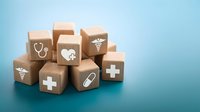 Wooden blocks with medical icons including stethoscope, caduceus, cross, and pill symbols stacked on a blue background.