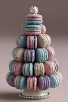 Festive tower of colorful macarons arranged in Christmas tree shape with pastel blue, pink, purple, and beige cookies decorated with sprinkles and pearl topper.