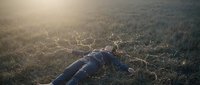 Young woman lying peacefully in golden meadow grass during sunset with warm sunlight creating dreamy atmospheric mood for wellness and relaxation concepts.