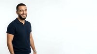 Young man with dark hair and beard, Mediterranean ethnicity, wearing navy blue polo shirt, smiling at camera against white background. Suitable for business, lifestyle, and promotional design projects.