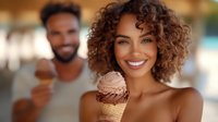 Young African American woman with natural curly hair enjoying ice cream cone outdoors on sunny day, with man in background. Genuine happiness and summer lifestyle.