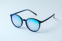 Modern round eyeglasses with black frame and blue gradient lenses on white background, isolated fashion accessory for optical and style concepts.