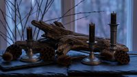 Rustic driftwood branch with vintage brass candlesticks and pine cones arranged on wooden surface near window with bare branches creating atmospheric decor.