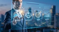 Professional businessman touching digital interface with business icons including growth, teamwork, target and analytics against city skyline at dusk.