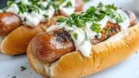 Grilled hot dogs in toasted buns topped with fresh herbs and creamy white sauce, close up view of gourmet street food with garnish and condiments.