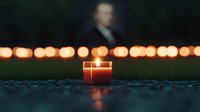 Glowing candle in glass jar at dusk with soft bokeh lights in background creates peaceful atmospheric mood for meditation, remembrance or spiritual moments.
