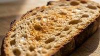 Sliced whole grain bread with visible air pockets and crust, showcasing texture for baking, nutrition, and food photography projects.