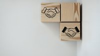 Wooden blocks with handshake symbols representing business partnership, teamwork and cooperation concepts for corporate presentations and marketing materials.