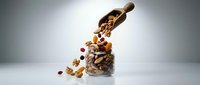 Wooden scoop pouring mixed nuts and dried cranberries into glass jar against white background, ideal for food and nutrition content.