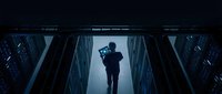 Business professional silhouette standing in modern data center server room with blue lighting and technology infrastructure for corporate concepts.