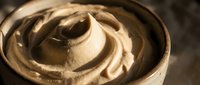 Creamy beige frosting swirl in bowl, ready for cake decorating, baking projects, and culinary design applications.