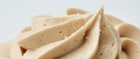 Creamy beige whipped dessert topping with swirled texture and visible speckles, isolated on white background for bakery, confectionery, and food design projects.