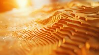 Macro photography of golden rippled surface with intricate wave patterns and light reflections creating abstract texture background with soft bokeh effect.
