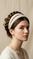Young Caucasian woman with elegant braided updo hairstyle wearing cream padded headband against neutral beige background for fashion and beauty concepts.