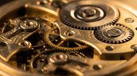 Intricate golden clockwork mechanism with precision gears, springs and mechanical components showcasing detailed craftsmanship and engineering excellence.