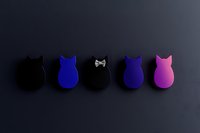 Minimalist cat silhouettes in black, blue and pink arranged in row on dark background. Simple geometric shapes create modern decorative pattern.