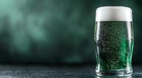 Green beer with foam head in pint glass against dark emerald background with bokeh effect, festive drink photography showing bubbles and condensation.