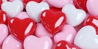 Colorful heart-shaped candies in red, pink and white creating romantic Valentine's Day sweets pattern for love celebration and holiday decorations.