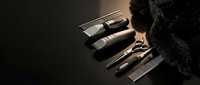 Professional grooming tools including clippers, scissors, and combs arranged on dark surface with black fur for barbering, salon, and personal care use.