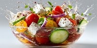 Fresh Greek salad with tomatoes, cucumbers, feta cheese and herbs splashing in glass bowl on white background. Healthy Mediterranean cuisine for restaurants.