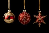 Elegant red and gold Christmas ornaments hanging on ribbons against black background, perfect for festive holiday designs.