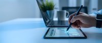 Professional using digital stylus pen on tablet for creative design work and digital art projects in modern office workspace.
