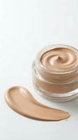 Open glass jar with beige foundation cream and makeup smear on white background. Cosmetic product for skincare and beauty routine isolated for design use.