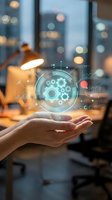 Hands holding holographic digital interface with gears and data analytics in modern office workspace for business technology and innovation concepts.