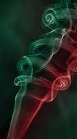 Abstract colorful smoke swirls in green and red hues creating elegant flowing patterns against dark background for creative design projects.