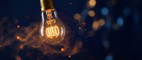 Glowing incandescent bulb with warm filament against dark background with bokeh particles, representing innovation, energy, and creative ideas for design projects.