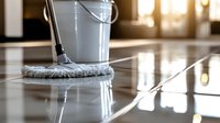 White mop cleaning shiny marble floor with bucket in luxury interior, sunlight through window creates reflective surface, professional housekeeping service.